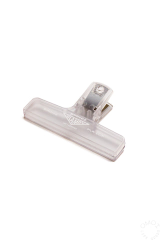 A clear penco binder clip on a white background