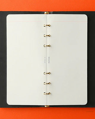Black ring-bound notebook on an orange background