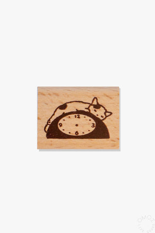 Wooden stamp with a design of a cat sleeping on a clock