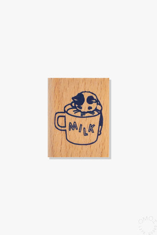 Wooden stamp with illustration of a cat drinking from a glass of milk