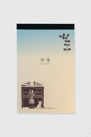 Notebook cover with gradient design and illustrations of cats on a piano on a white background