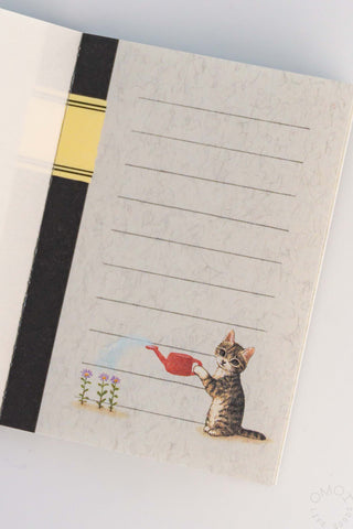 Notebook with a cat watering plant illustration on a white background