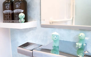 Two small blue SMISKI bath figures beside a shelf and bathtub