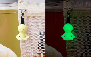 Two glow-in-the-dark zipperbite charms on fabric zippers, yellow and green