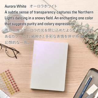 Notebook on a wooden surface with stationery items and text about Aurora White color.