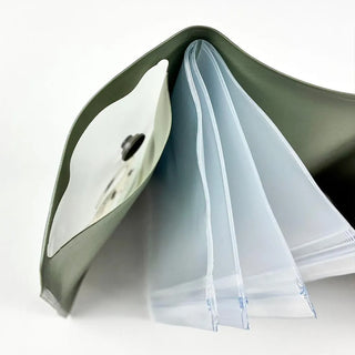 Small green pouch folded open, showing layered interior pockets and zipper edges.