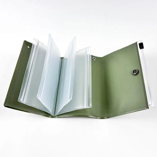 Small green pouch opened wide, showing multi-slot interior and clear zipper sides.