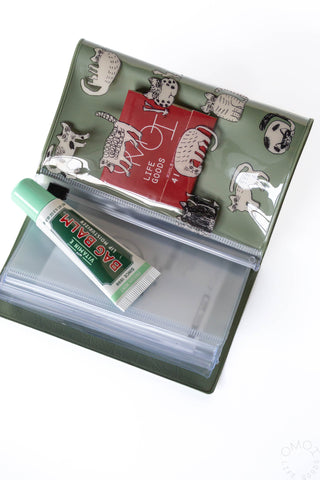 Small green pouch open flat, holding multiple items in transparent compartments.