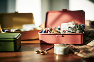 Open pink toolbox with craft items on a wooden surface