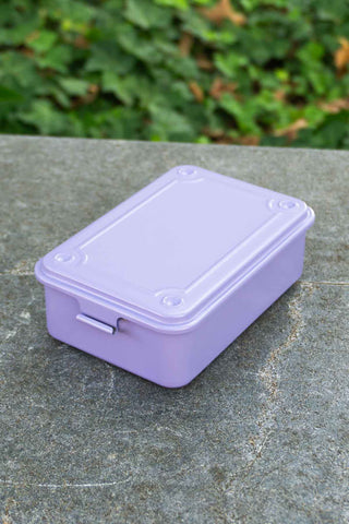 Purple trunk toolbox on a stone surface with green foliage in the background