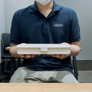 White trunk-shaped toolbox held by a person, closed with molded lid.