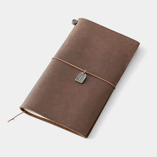 Brown leather notebook cover with pewter charm luggage tag tied to the strap