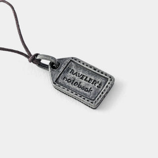 Engraved TRAVELER'S FACTORY pewter charm tag on dark cord