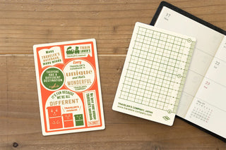 Passport writing mat with orange patterned cover beside open planner pages