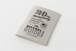Traveler's notebook with '20th Anniversary' and 'History Guide' text on a white background