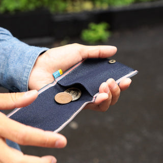 Person holding open Beams Japan denim coin purse with coins