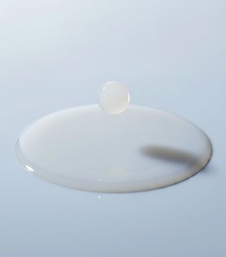 Smooth white essence gel pool with a small drop on a glossy surface