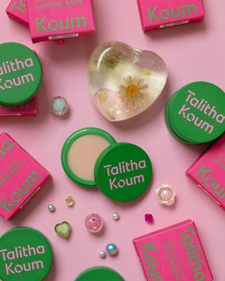 Green Talitha Koum lipcure balm tins and pink lipcure balm boxes, scattered