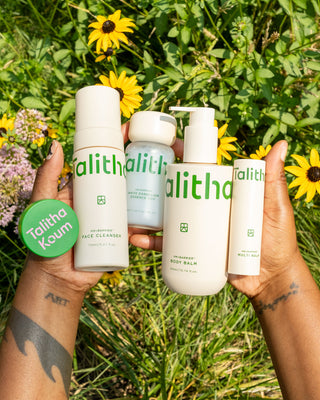 Talitha Koum lipcure balm tin in hands, with white skincare bottles nearby