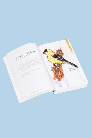 Open book with illustration of an American Goldfinch on a light blue background