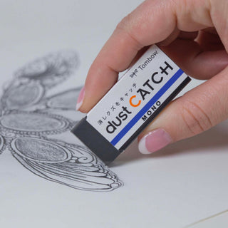 MONO Dust Catch eraser labeled Dust Catch, held over printed line art