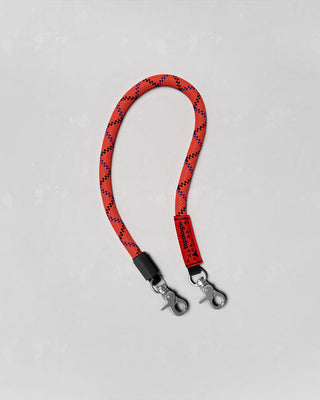 Red and black patterned wrist strap with a clip on a light gray background