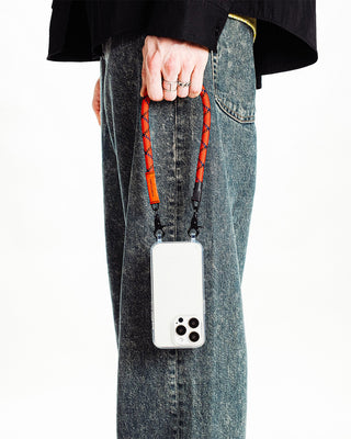  Person holding orange and dark blue wrist strap attatched to a phone