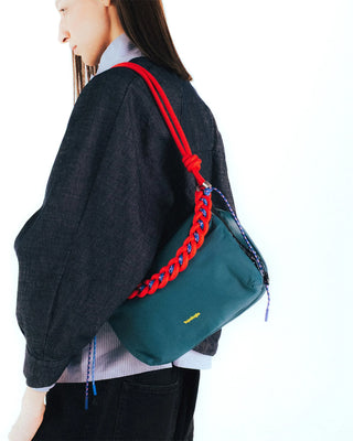 Red braided O-rope strap worn over shoulder, with metal clips at ends