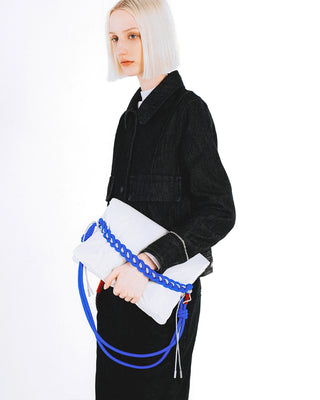 Person holding a white bag with a bright blue adjustable rope strap