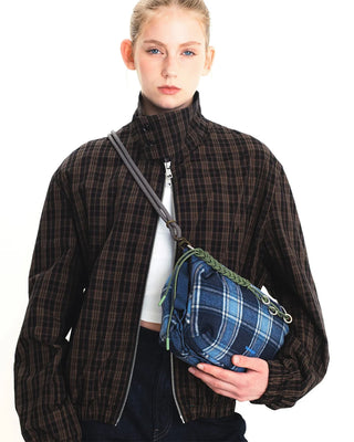 Person wearing plaid jacket with blue plaid bag with patterened black and white bag strap