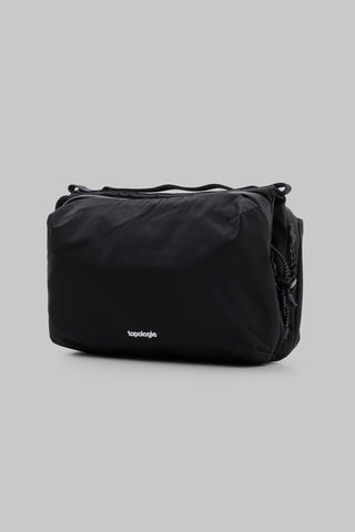 A black bag from topologie featuring a small white logo on the front, set against a solid gray background.