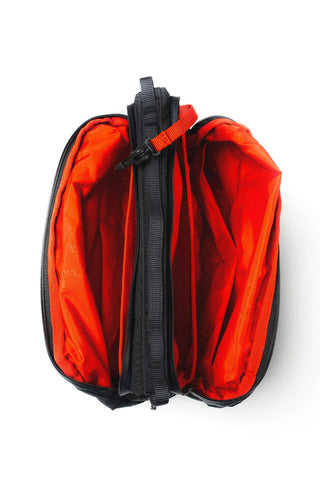 An open zippered bag with a bright orange-red interior and black exterior trim, photographed from above on a plain white background.