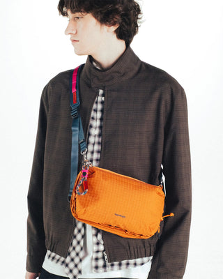 Person wearing an orange grid bag with a wide adjustable strap