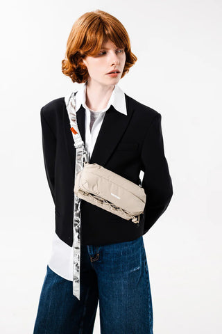 Taupe crossbody puffer bottle sling bag worn diagonally over blazer model