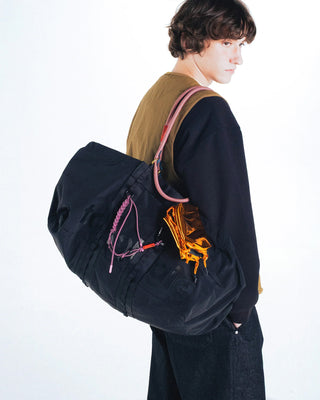 Person wearing big duffel bag with multiple straps and keychains attatched