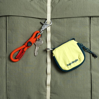 Olive helmet bag close-up with key clip, zipper pull, and small topologie pouch