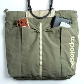 Olive helmet bag front with rope handles, phone slots, and topologie label