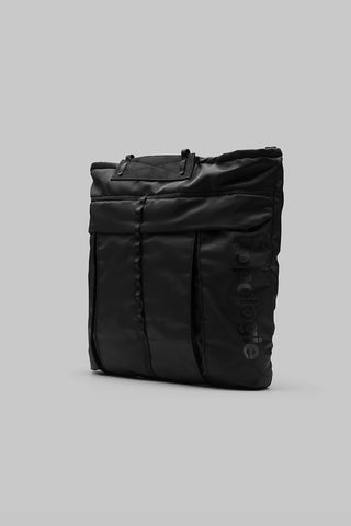 Black helmet bag with top handle, front pocket panel, and side straps
