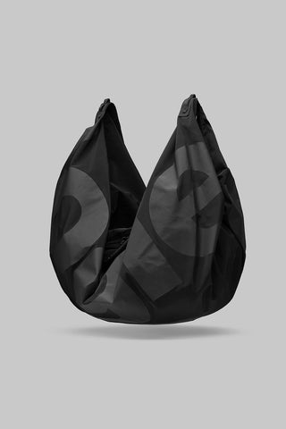 A black slouchy shoulder bag with large letters on bag, against a solid gray background.