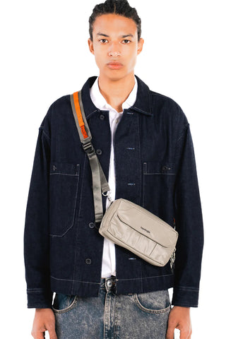 Light gray utility sling bag with wide strap and front flap pocket