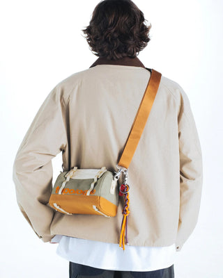 Person wearing a beige jacket with a crossbody bag on a white background