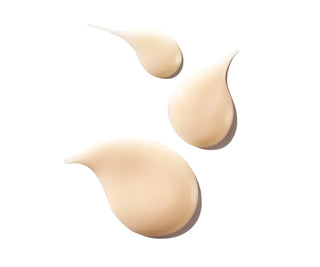 Three droplets of beige cream on a white background