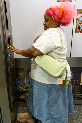 Person with pink hair using an elevator, wearing a white shirt and blue skirt.