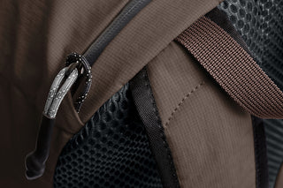 Close-up of a brown backpack with a zipper and mesh pocket.