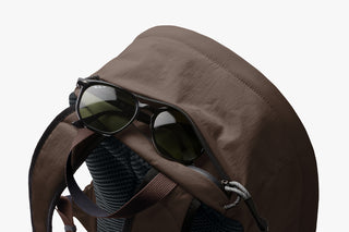Brown backpack with sunglasses on a white background