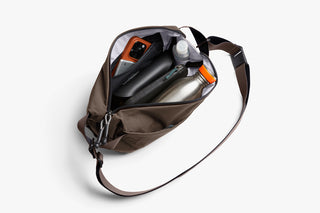 Opened sling bag with personal items inside such as water bottle and wallet, phone
