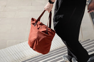 Person walking down steps holding tote bag in hand
