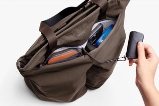 Brown bag with opened zipper to show items and hand holding keychain