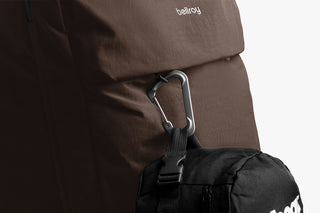 Close-up of a brown backpack with a carabiner attached, featuring Bellroy branding logo