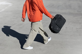 Person walking on a road holding a black bag